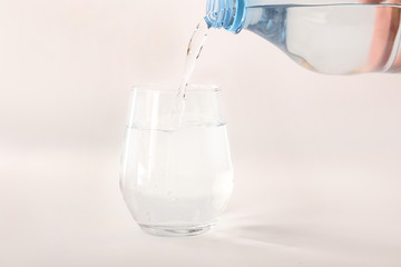 Pouring of water into glass on white background
