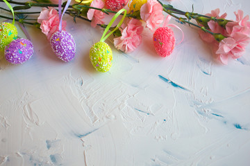  Easter eggs and flowers on a light background. Holiday card for Easter. Colored eggs and pink flowers