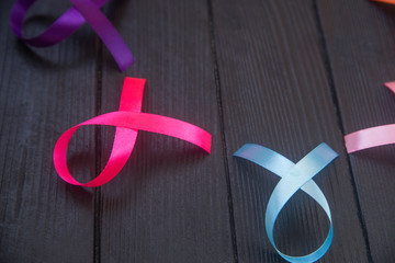 Close up of cancer ribbons on black wooden background. Cancer awareness month.