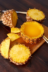 Fresh fruit juice with exotic pineapple on a wooden brown table. A composition made of ananas. Top wiev. 