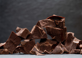 Dark or milk organic chocolate pieces on dark concrete backgound