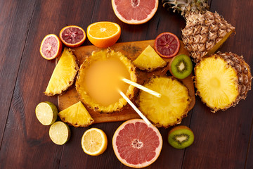 Fresh fruit juice with exotic fruits on a wooden brown table. A composition made of grapefruit, lemon, lime, pineapple, orange. Top wiev. 