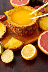 Fresh fruit juice with exotic fruits on a wooden brown table. A composition made of grapefruit, lemon, lime, pineapple, orange. Top wiev. 