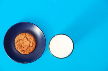 cookies and glass of milk on blue background. oatmeal cookie with pieces of chocolate