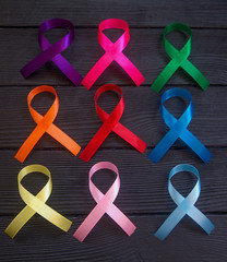  Cancer ribbons on black wooden background. Cancer awareness month.