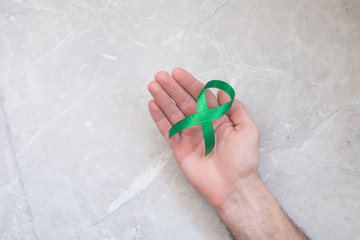 Man holding green cancer ribbon, symbol of lymphoma. Concept of health and medicine.