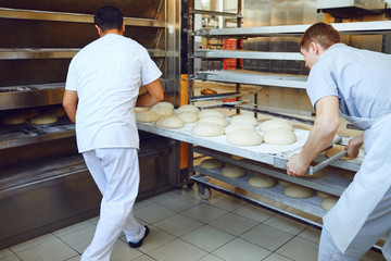 Bakers are pushing a tray of bread into the oven at the bakery.