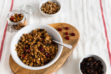 Bowl of homemade granola with nuts and fruits on white linen background. Side view, copy space. Healthy breakfast concept