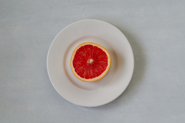 A slice of grapefruit on a white plate.