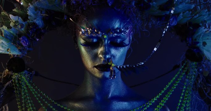 Portrait of beautiful female with complex floral make-up posing in creative lighting. Body painting fashion project. Model and property released. 4K UHD RAW FOOTAGE