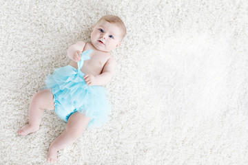 Adorable baby girl on white background wearing turquoise tutu skirt. Cute little child laughing and smiling. Happy carefree baby. Childhood, new life concept © Irina Schmidt