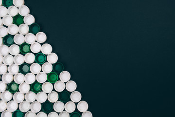 Plastic pollution concept. White and green plastic lids on dark background located diagonally. Single-use plastic. Refuse single-use plastic concept. Save ecology