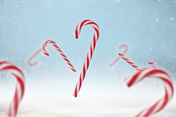 Red and white candy cane on a blue snowy background.