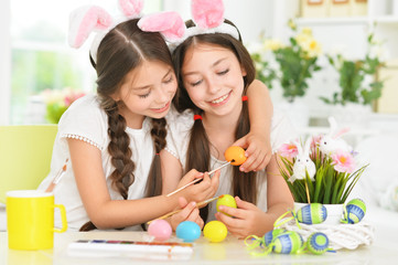 Cute twins wearing rabbit ears decorating Easter eggs
