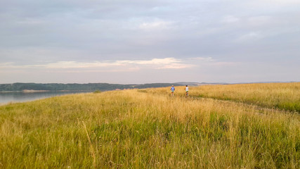 twgirls go by bicycles on the way to the field near the river
