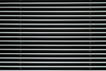 Closed window blinds. Light makes its way through closed blinds.
