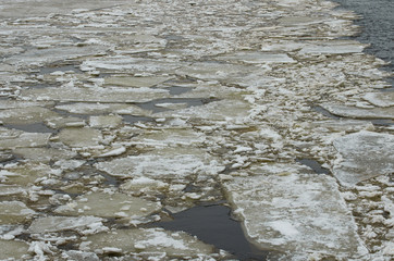 Floating cracked ice and sludge on river