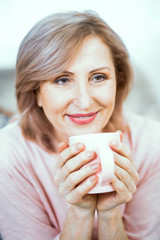 Happy mature woman with cup of tes in her hands