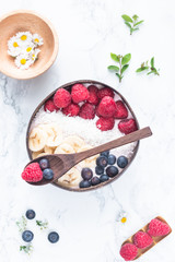 Healthy breakfast bowl. Banana smoothie bowl with coconut flakes, banana slices, raspberry and blueberry. Top view, flat lay