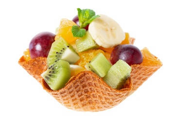 mix of fresh cuted fruits in waffle cone bowl is isolated on white background, concept of healthy dessert for children