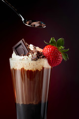 Chocolate drink with whipped cream, strawberry and pieces of black chocolate.