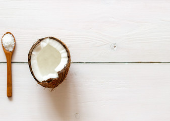 Coconut and spoon on a white wooden backdrop.
