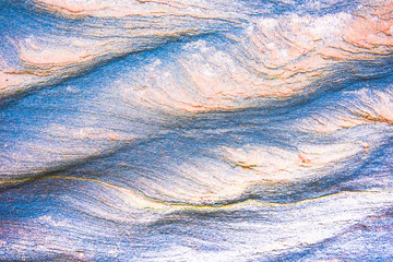 Abstract blue, gray, orange and green background - layers of rocks exposed by sea in Northumberland