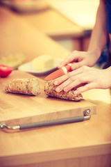Obraz premium Woman making sandwich cutting bread