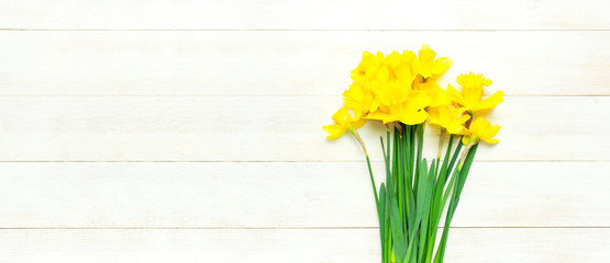 Spring floral background. Yellow narcissus or daffodil flowers on white wooden background top view flat lay. Easter concept, International Women's Day, March 8, holiday. Card with flowers copy space