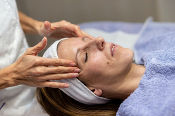Obraz na płótnie Canvas Young brunette enjoying cleansing facial massage