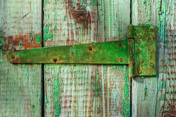 Green shabby door hinge on old green wood door with cracked and scratch. Horizontal grunge texture