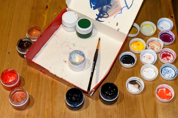 Open cans of paint and brush on wooden background, full house on table
