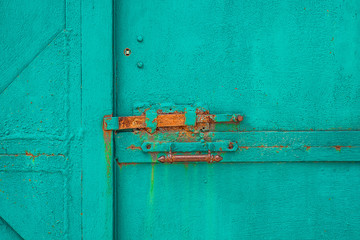 Lock and latch on metal green door with cracked and scratch. Horizontal grunge texture