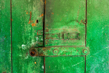 Lock and latch on wood green door with cracked and scratch. Horizontal grunge texture