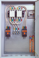Electrical Cabinet with contactors, circuit breakers, voltage relays and through terminals. Electrical cables are connected to circuit breakers, starters, through terminals and relays.