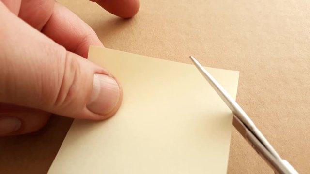 Cutting corners idiom Briticism hand takes sheet of paper and cutting corners by scissors doing something so easily and cheaply as possible 