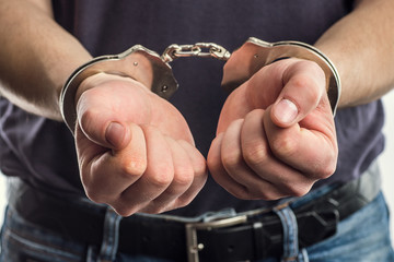 Adult male arrested and handcuffed.Man under Arrest. Hands with handcuffs in the front.Man with his...