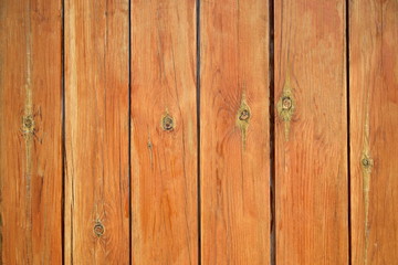 A fence from the tightly nailed wooden planks. Natural color of pine wood covered with transparent varnish. Close-up. Selective focus. Copy space. 