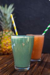 glass is filled with fresh and useful smoothie made from spicy juicy vegetables and fruits. Drink is sitting on a wooden table near the ingredients from which it is cooked illuminated by warm daylight