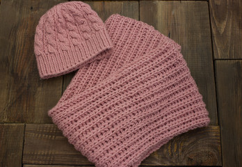 Pink, warm, winter, cozy, soft knitted hat and handmade scarf on a brown background.