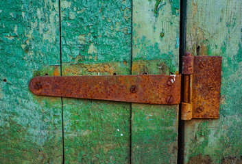 Rusty door hinge on old green wood door with cracked and scratch. Horizontal grunge texture