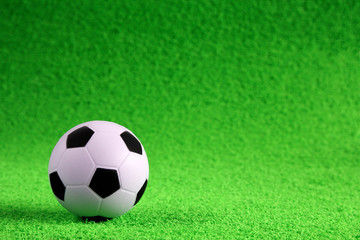 Small soccer ball on a green artificial football field. Football concept.