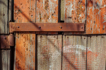 Rusty Door hinge on wood door cracked and scratched, with remnants of red paint. Horizontal grunge texture