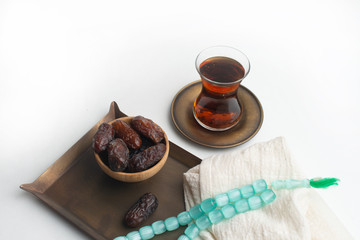 Ramadan Kareem Festival, Dates on wooden bowl with cup of black tea and rosary on white isolated background