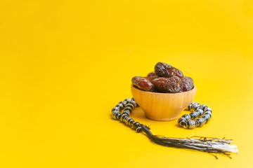 Fototapeta na wymiar Ramadan Kareem Festival, Dates at wooden bowl with rosary on yellow background