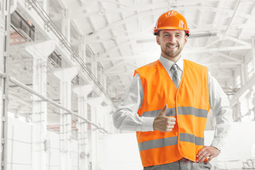 The builder in orange helmet against industrial background