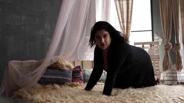 Model plus size with big cheeks and black hair lies almost naked on the bed