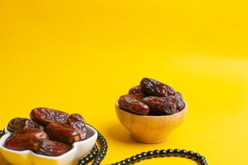 Ramadan Kareem Festival, Dates at bowl with rosary on yellow background