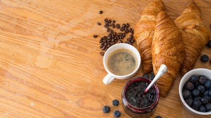 Rogaliki croissant z dżemem owocami i kawą leżące na drewnianym blacie