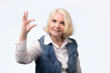 senior woman showing small size sign with fingers